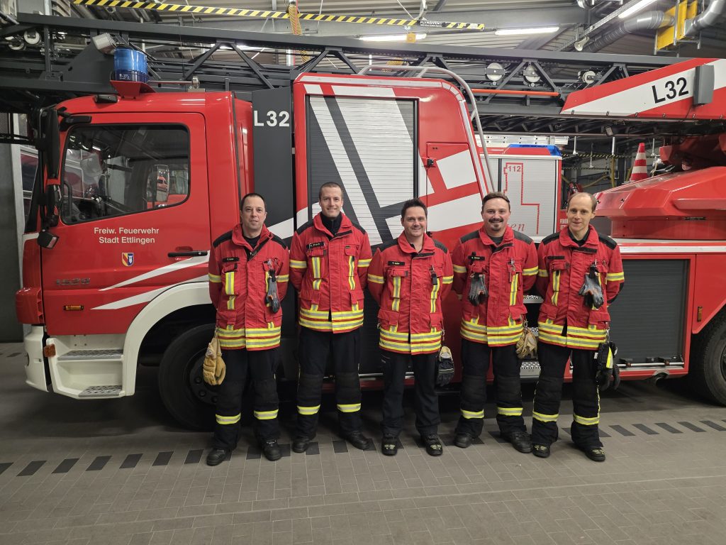 Bild mit Lehrgangsteilnehmern vor der Drehleiter, 5 Personen